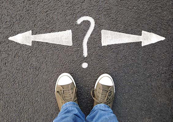A person stands on a road with arrows pointing in either direction and a question mark.