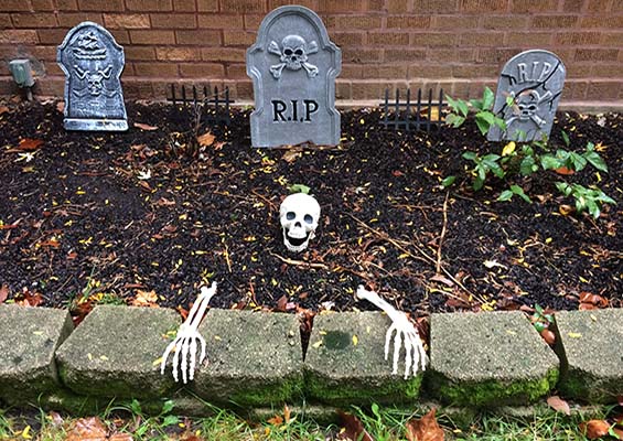 A skeleton coming out of the ground in a graveyard