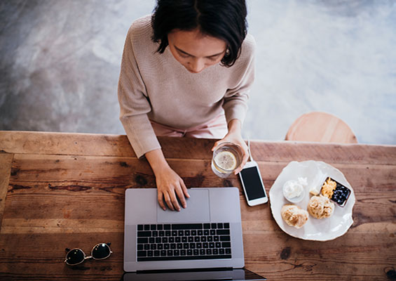 A woman looking at her phone and her laptop