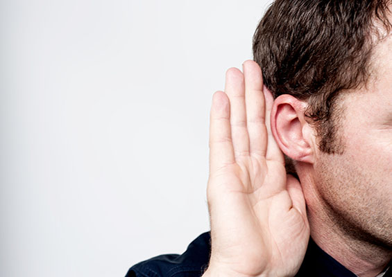 A man holds his hand up to his ear to hear a secret